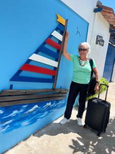 a woman standing next to a staircase with a suitcase at Casa quadra praia Jacaraipe! in Jacaraípe +3 photos