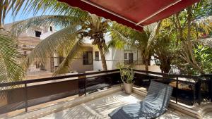 a balcony with two chairs and palm trees at Jade guest House in Dakar