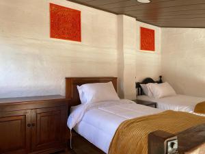 a bedroom with two beds and red paintings on the wall at Cabañas San Carlos - Puembo Centro in Puembo