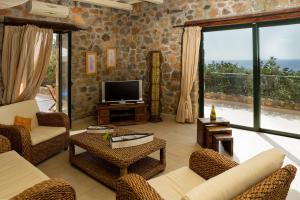 een woonkamer met meubilair en een groot raam bij Artemis Villa with Amazing Sunset Views & Private Pool,near Elafonissi in AmigdhalokeFálion