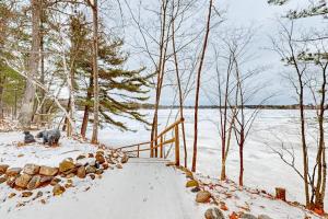 a snow covered walkway next to a body of water at Stormy Point Cabin in Conover