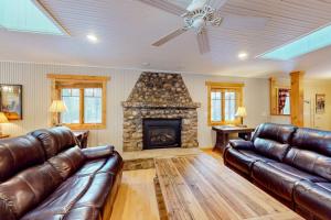 a living room with leather furniture and a stone fireplace at Moon Ridge Lodge in Saint Germain
