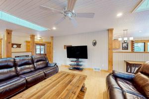 a living room with a leather couch and a flat screen tv at Moon Ridge Lodge in Saint Germain +42 photos
