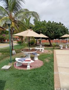 a group of picnic tables with umbrellas in a park at Conjunto Costa Grande villas in Higuerote
