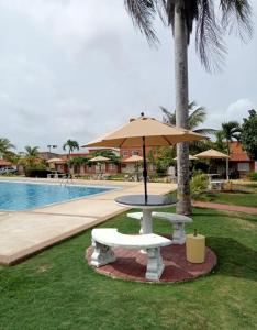 a picnic table with an umbrella next to a pool at Conjunto Costa Grande villas in Higuerote