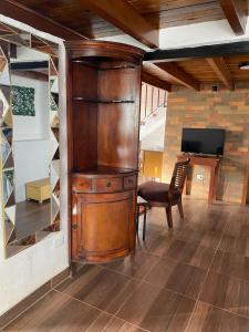 a large wooden cabinet in a room with a chair at Cabañas San Carlos - Puembo Centro in Puembo +2 photos