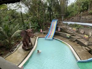 a person in a swimming pool with an elephant statue at Jagadhita Villas in Sekatonan