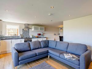 a living room with a blue couch and a kitchen at 2 Bed in Holmfirth oc-emley in New Mills