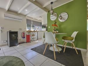 a living room with two white chairs and a green wall at Bungalow Sonnerust in Lanaken