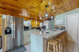 a kitchen with wooden ceilings and a large island with bar stools at Roaming Deer Cottage in Saint Germain