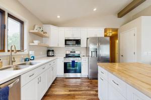 a kitchen with white cabinets and a stainless steel refrigerator at Rome Retreat- Steps from Beach & Golf in Nekoosa