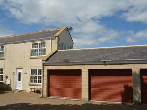 a garage with two red garage doors in front of a house at 2 Bed in Morpeth oc-36925 in Widdrington