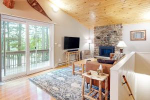 a living room with a stone fireplace and a tv at Hillis House in Arbor Vitae