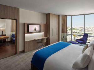 a hotel room with a large bed and a desk at Novotel Jeddah Tahlia in Jeddah