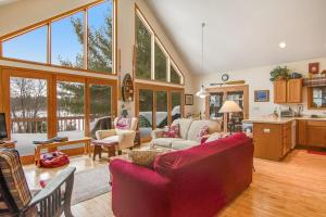a living room with a red couch and a kitchen at RTLCMP Lakehouse in Arbor Vitae