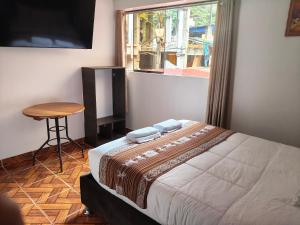 a bedroom with a bed and a table and a window at Hostal Ñustas INN in Machu Picchu
