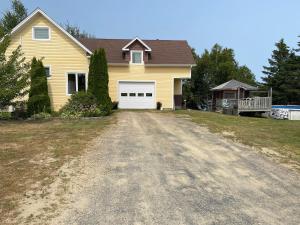 a yellow house with a white garage at 5 bedroom Waterfront house in Tracadie