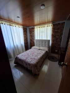 ein Schlafzimmer mit einem Bett in einem Zimmer mit Fenstern in der Unterkunft Suame in Sogamoso