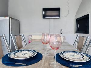 a table with two wine glasses and plates on it at Casa de Fundos com 2 QuartosWi-fi e Estacionamento in Lages