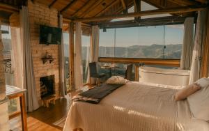 a bedroom with a bed and a fireplace with a view at Montanha Home in Monte Verde