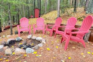 a group of pink chairs around a fire pit at Little Red Lakeside Cabin in Three Lakes