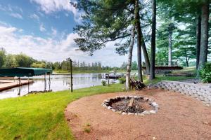 a fire pit in the grass next to a lake at Tall Pines in Woodruff