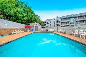 a large swimming pool with white chairs and tables at Lighthouse Cove Condo Resort: 418 in Wisconsin Dells