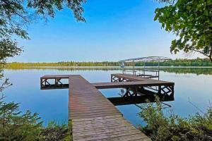 a dock on a lake with two benches on it at Watermelon Retreat & Suite in Three Lakes