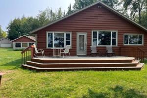 a house with a deck with chairs and a table at Watermelon Retreat & Suite in Three Lakes