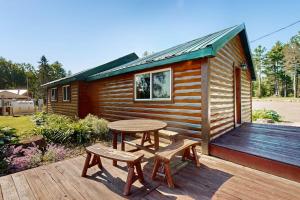 a cabin with a table and two benches on a deck at The Hunters Den in Mercer