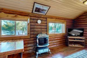 a log cabin with a television and a stove at The Hunters Den in Mercer