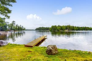 a dock on a lake with a rock in the grass at Wild Bear Retreat in Saint Germain