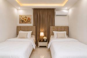 two beds in a hotel room with white sheets at Luxurious Beachfront Apartment in Alexandria