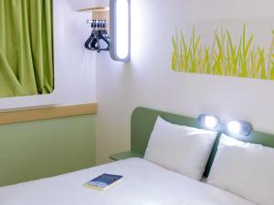 a bedroom with a bed with a remote control on it at ibis budget Osasco in Osasco