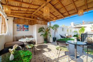 a patio with tables and chairs and a couch at Riad Nadalinn in Marrakesh