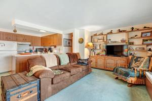 a living room with a large couch and a kitchen at Hotter's Cabin in Eagle River