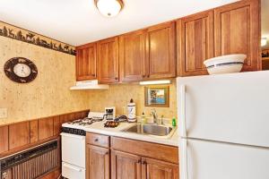 a kitchen with wooden cabinets and a white refrigerator at Cleerwood Village #252 in Eagle River