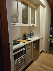 a kitchen with white cabinets and a stove top oven at Hill Top Park - Apple Tree Studio in Kilmore