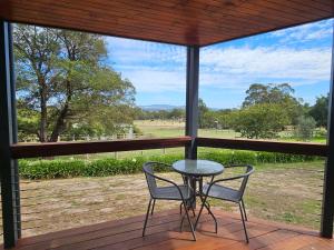 a table and chairs on a porch with a view of a field at Hill Top Park - Apple Tree Studio in Kilmore +27 photos