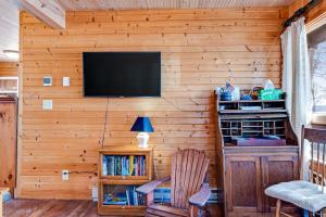 a living room with a television on a wooden wall at Bucky's PineIsle Retreat in Three Lakes