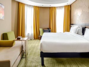 a hotel room with a large bed and yellow curtains at ibis Styles Makkah in Mecca
