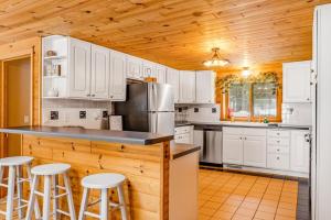 a kitchen with white cabinets and a counter with stools at The Haven in Eagle River +16 photos