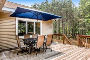 a table with chairs and a blue umbrella on a deck at Peaceful Pines in New Rome