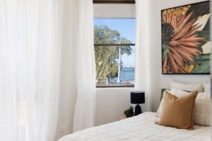 a white bedroom with a bed and a window at Coastal Bliss in Lemon Tree Passage
