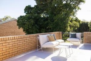 two chairs and a table next to a brick wall at Coastal Bliss in Lemon Tree Passage