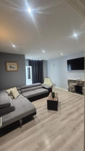 a large living room with a couch and a tv at Easy Stay Jerviston in Mossend