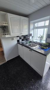 a kitchen with white cabinets and a sink and a window at Easy Stay Jerviston in Mossend