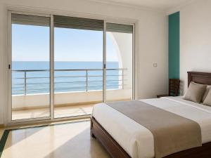 a bedroom with a bed and a view of the ocean at Seaside Mediterranean Duplex in Kelibia