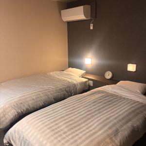 a room with two beds and a clock on the wall at ホテル　ロマン in Koshimizu-shigai
