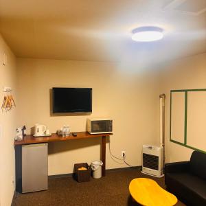 a room with a desk and a tv on a wall at ホテル　ロマン in Koshimizu-shigai +4 photos